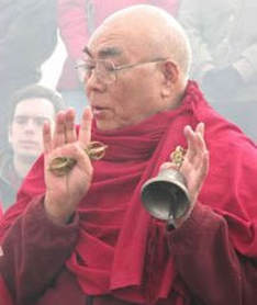 Lama Lodu Rinpoche in red robes, giving blessing