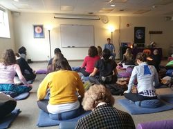 Large group of people sitting on cushions during a guided breath class