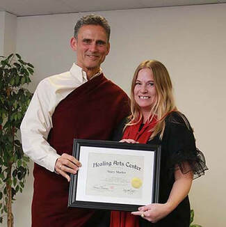 Stacy Marler receives her certificate of completion from Headmaster, Tom Tessereau, from the Massage Program at the Healing Arts Center